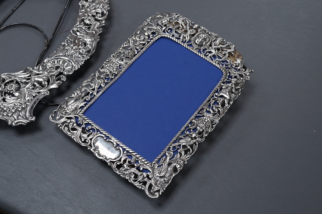 A late Victorian German Hanau silver photograph frame, pierced and decorated with mask, scrolls, figures and animals, import marks for Thomas Glaser, London, 1893, 23.7cm, gross weight 8.7oz, together with one other smal